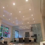 Photo of a glossy stretch ceiling with built-in lamps in the living room combined with the kitchen
